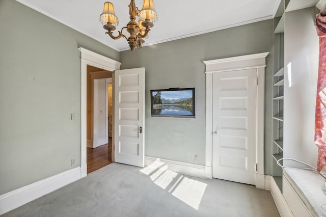 unfurnished bedroom with baseboards, ornamental molding, carpet, and an inviting chandelier