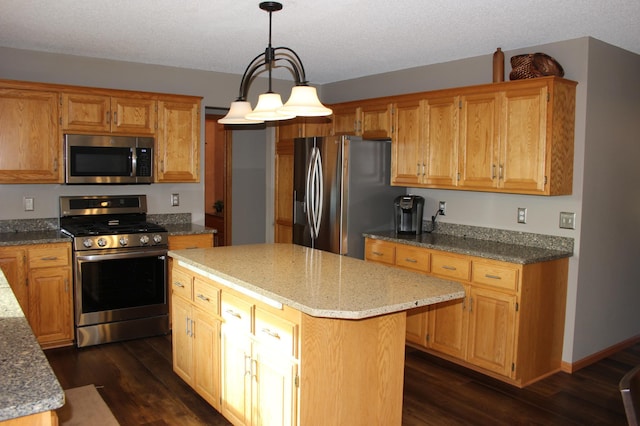 kitchen with dark wood-style floors, appliances with stainless steel finishes, a center island, and light stone countertops