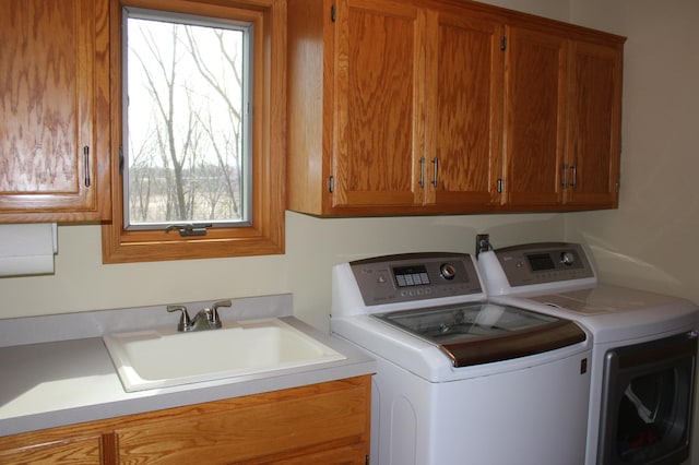 laundry area featuring washer and dryer, cabinet space, and a sink