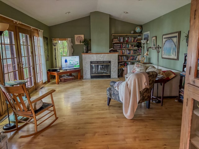 sitting room featuring a tile fireplace, french doors, lofted ceiling, and wood finished floors