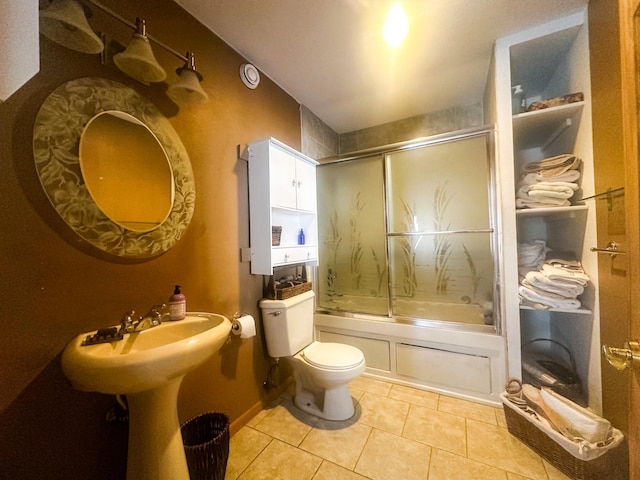 full bathroom with toilet, tile patterned flooring, and bath / shower combo with glass door