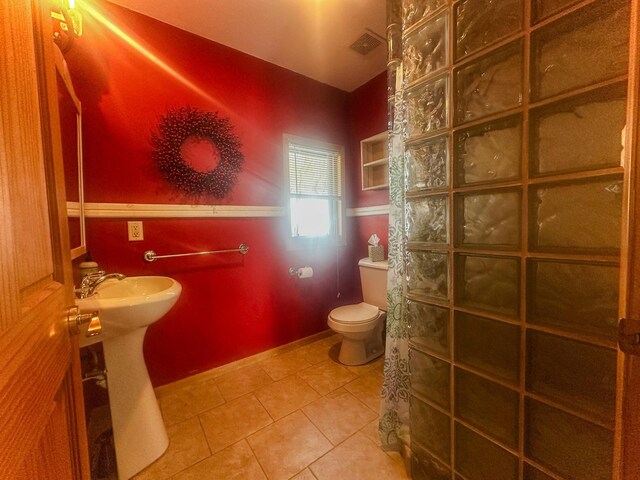 bathroom featuring toilet, a sink, visible vents, tile patterned floors, and walk in shower