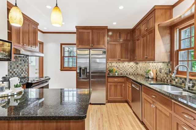 5824 10th Ave S, Minneapolis, MN 55417 - kitchen featuring stainless steel appliances, a sink, under cabinet range hood, pendant lighting, and light wood-type flooring