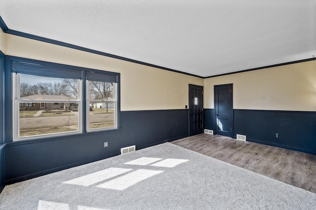 1610 Hennepin Ave N, Glencoe, MN 55336 - empty room featuring wainscoting, crown molding, a textured ceiling, and visible vents