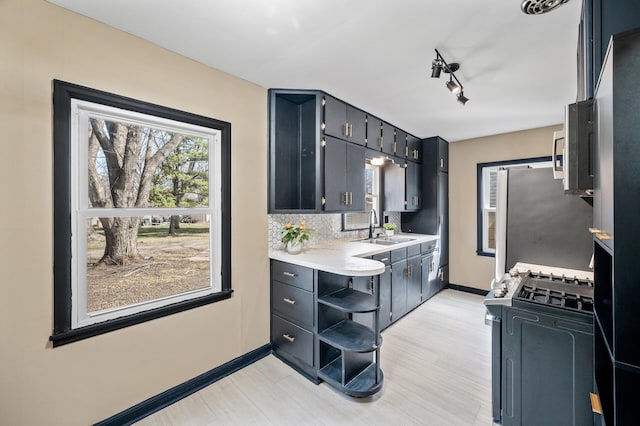 1610 Hennepin Ave N, Glencoe, MN 55336 - kitchen with open shelves, a sink, light countertops, gas range oven, and baseboards