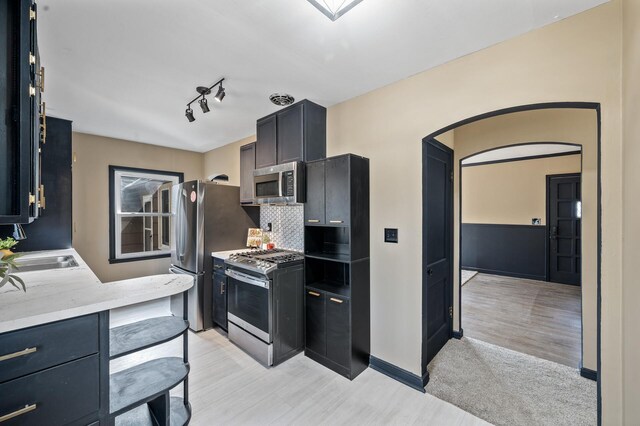 1610 Hennepin Ave N, Glencoe, MN 55336 - kitchen with backsplash, a sink, arched walkways, light wood-style floors, and appliances with stainless steel finishes