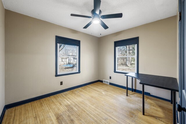 1610 Hennepin Ave N, Glencoe, MN 55336 - unfurnished room with visible vents, a ceiling fan, wood-type flooring, baseboards, and a textured ceiling