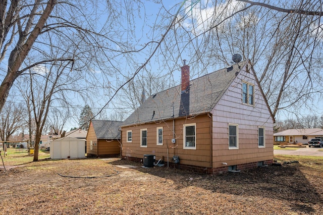 1610 Hennepin Ave N, Glencoe, MN 55336 - back of house with a storage unit, an outbuilding, central air condition unit, a chimney, and a shingled roof
