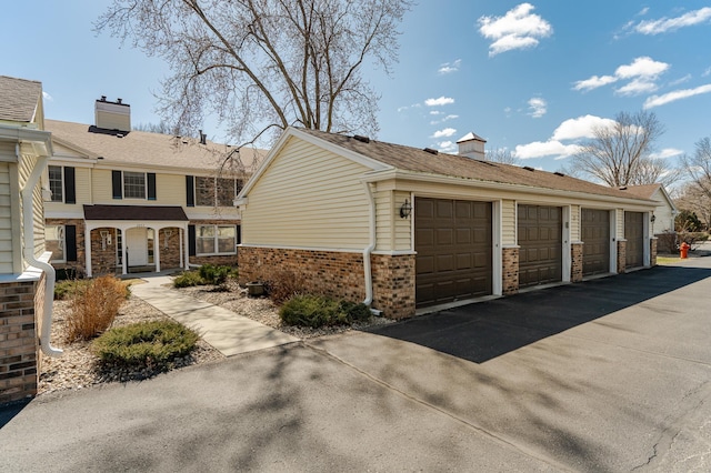 2053 Carriage Dr SW Unit 2053E, Rochester, MN 55902 - view of side of home with community garages, a chimney, and brick siding