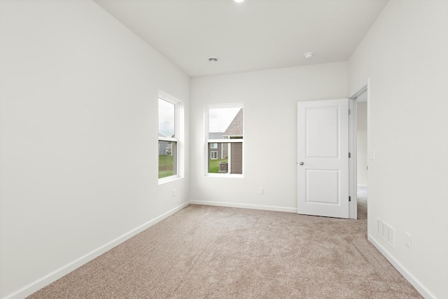 unfurnished room featuring visible vents, baseboards, and light carpet