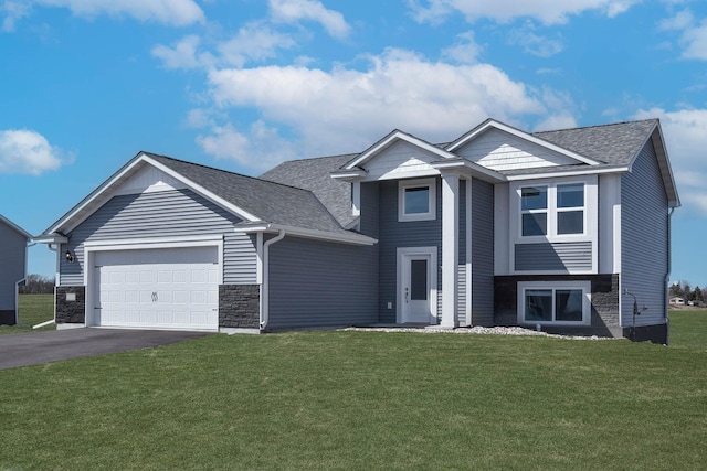 view of front of home featuring an attached garage, driveway, a front lawn, and roof with shingles