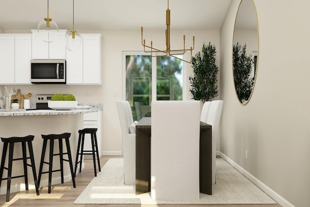 dining space featuring light wood finished floors, a chandelier, and baseboards