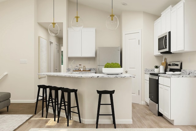 kitchen featuring light wood-style flooring, appliances with stainless steel finishes, a breakfast bar area, white cabinets, and vaulted ceiling