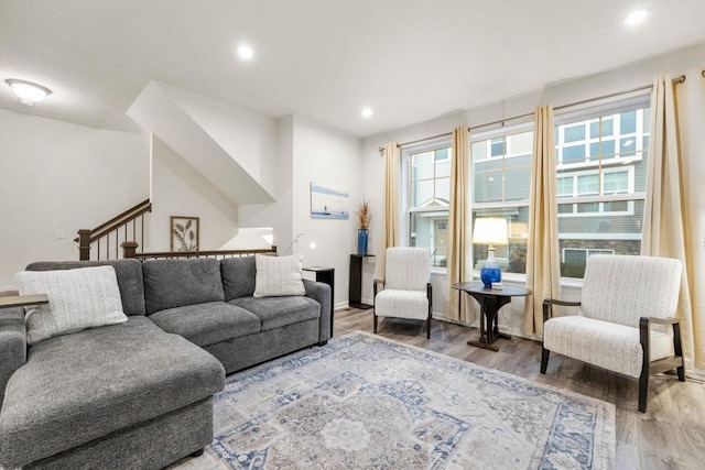 living room featuring stairs, baseboards, wood finished floors, and recessed lighting