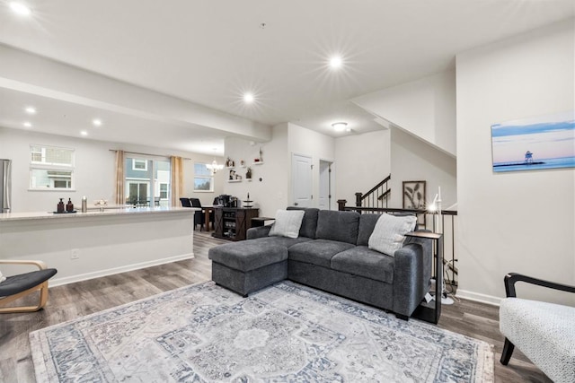 living room featuring a chandelier, recessed lighting, wood finished floors, baseboards, and stairs