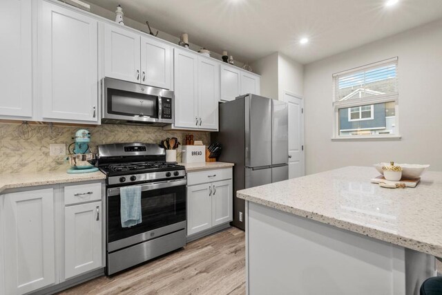 kitchen with light wood-type flooring, tasteful backsplash, white cabinetry, and stainless steel appliances