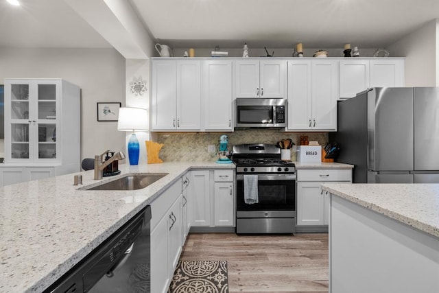 kitchen featuring white cabinets, appliances with stainless steel finishes, decorative backsplash, and a sink