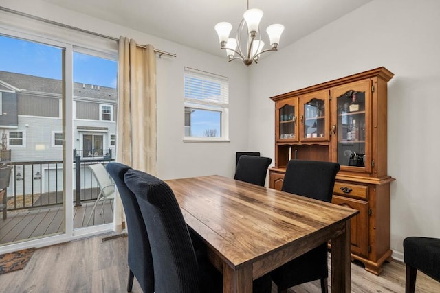 dining space featuring light wood-style flooring, a chandelier, and baseboards