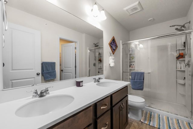 bathroom with double vanity, a sink, visible vents, and a shower stall