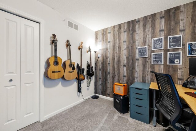 office area with baseboards, wooden walls, visible vents, and carpet flooring