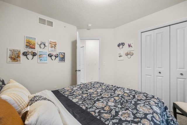 bedroom with a textured ceiling, visible vents, a closet, and carpet flooring