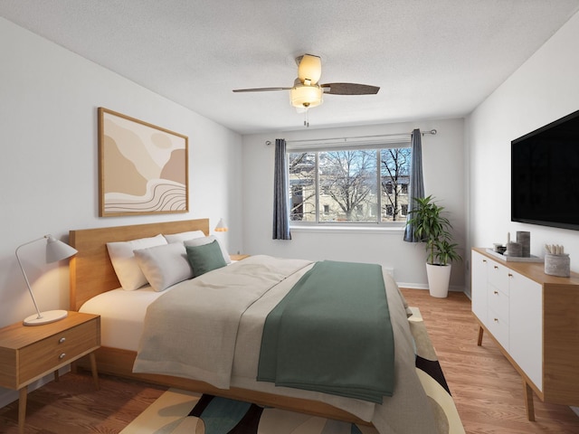 bedroom featuring light wood-style flooring, ceiling fan, and a textured ceiling