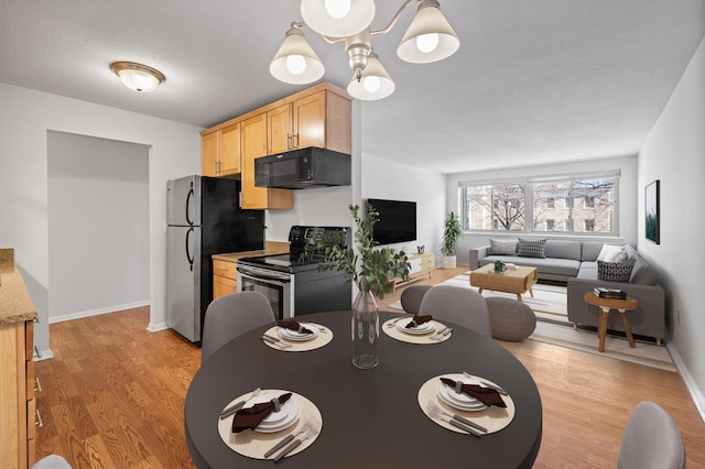 dining space featuring a chandelier, light wood-style flooring, and baseboards