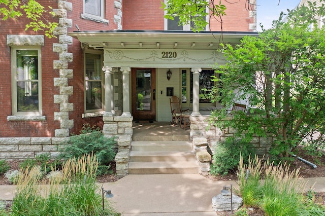 property entrance with a porch and brick siding