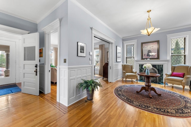 living area with light wood-style flooring, plenty of natural light, a high end fireplace, and wainscoting