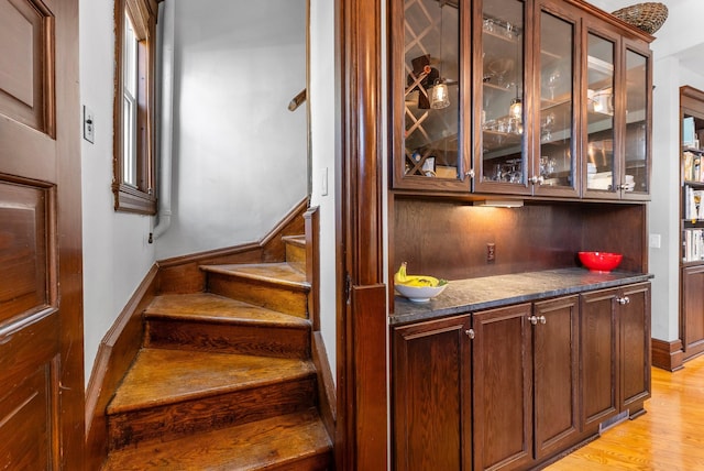 bar featuring light wood finished floors, stairway, and baseboards