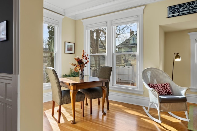 dining space with light wood finished floors, baseboards, a wealth of natural light, and ornamental molding