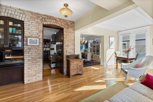 foyer entrance with beam ceiling, baseboards, light wood finished floors, and a chandelier