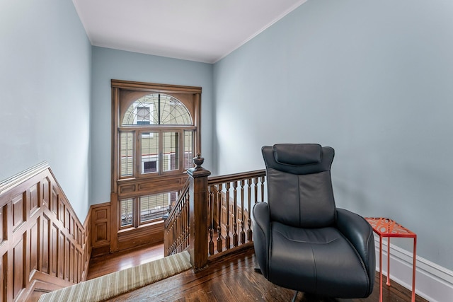 living area with an upstairs landing, a wainscoted wall, crown molding, and wood finished floors