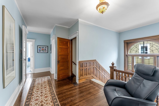 sitting room featuring dark wood finished floors, crown molding, an upstairs landing, and baseboards