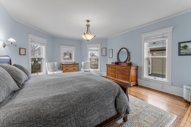 bedroom with wood finished floors, baseboards, and ornamental molding