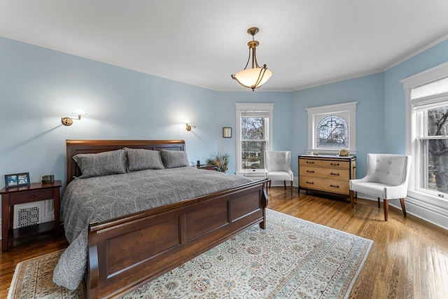 bedroom featuring visible vents, baseboards, dark wood finished floors, and crown molding