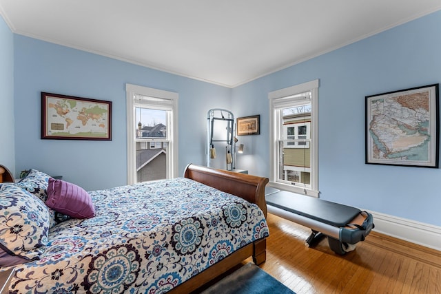 bedroom with hardwood / wood-style floors, baseboards, multiple windows, and ornamental molding