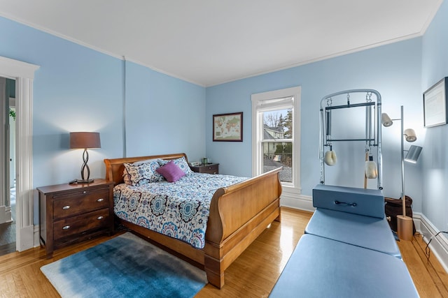 bedroom with ornamental molding and wood finished floors