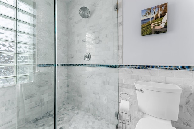 full bath featuring toilet, a stall shower, and tile walls