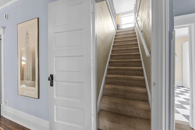 stairs with tile patterned floors, crown molding, and baseboards