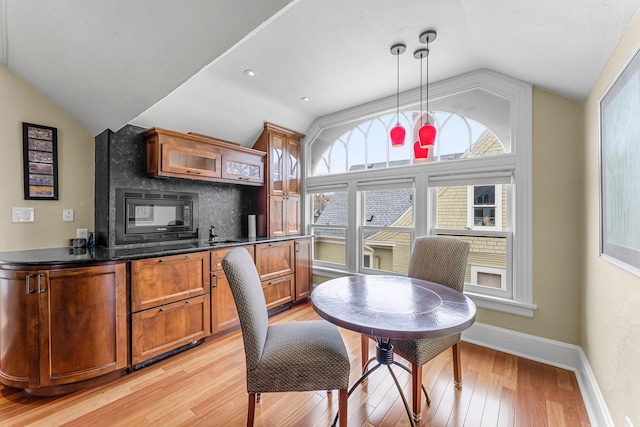 dining space featuring light wood-type flooring, lofted ceiling, and baseboards