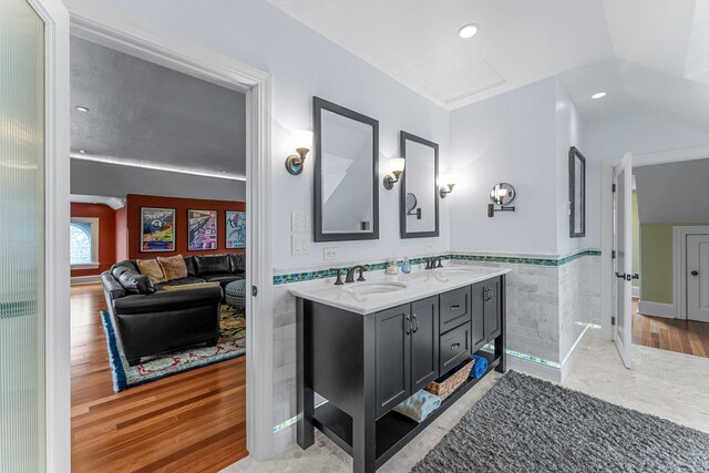 bathroom with tile walls, wood finished floors, a wainscoted wall, and a sink