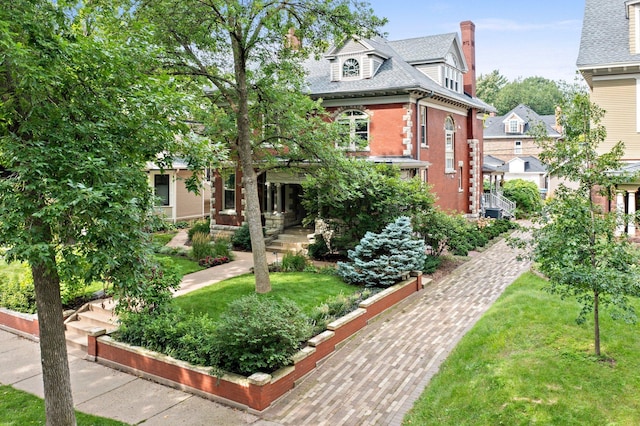 view of front facade featuring brick siding, a front lawn, and roof with shingles