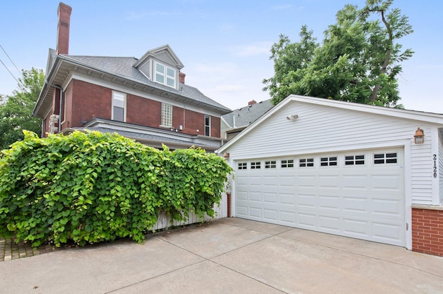 view of front of home with a garage, an outbuilding, brick siding, and driveway