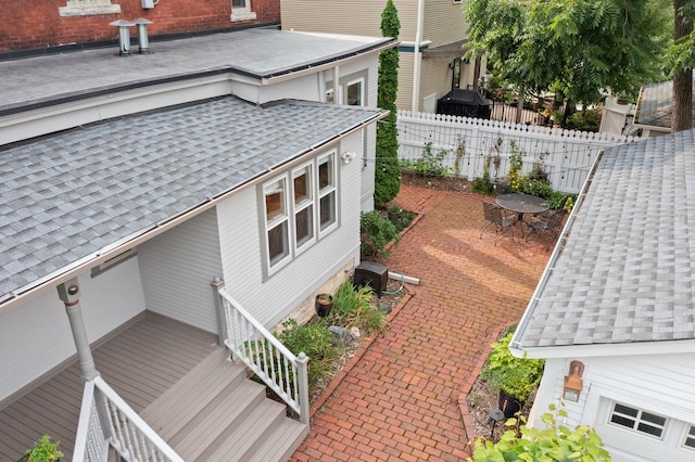 view of property exterior featuring cooling unit, roof with shingles, and fence