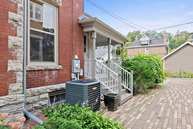 exterior space with central AC unit and brick siding