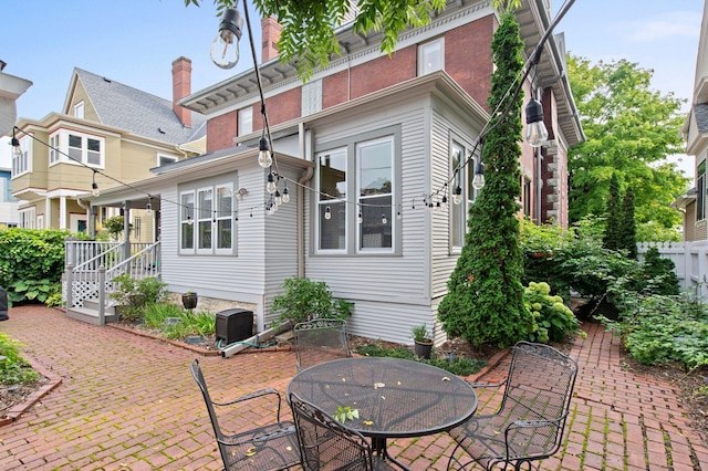 rear view of property with a patio area, outdoor dining space, and fence