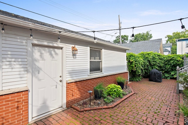 property entrance with a patio and brick siding