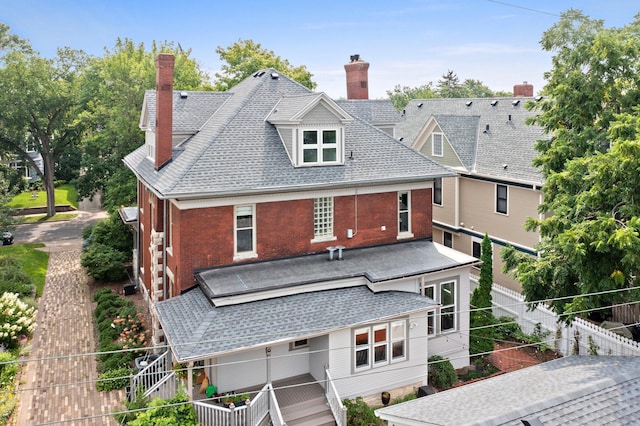 back of property with a chimney, brick siding, and roof with shingles