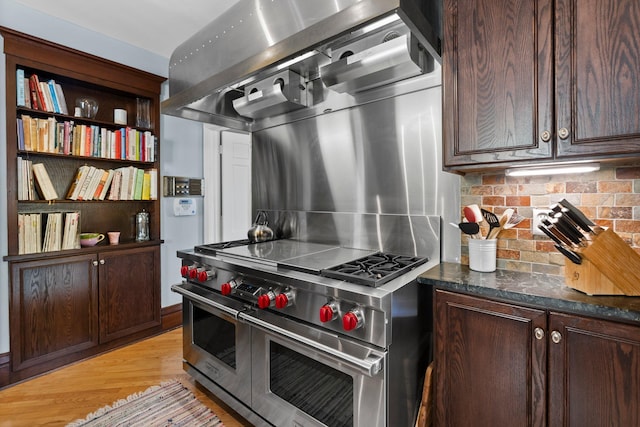 kitchen featuring dark brown cabinetry, range with two ovens, tasteful backsplash, and light wood-type flooring